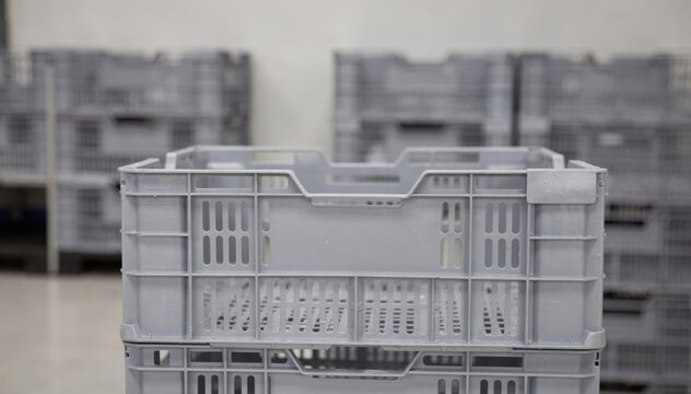 Medium shot of reusable crates stacked neatly at a rental packaging station main crate in sharp focus while background blurs softly.