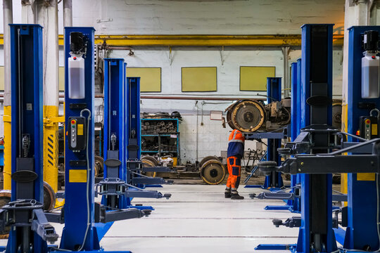Blue-colored car lifts located in a row in an auto repair shop or garage with several car service stations.