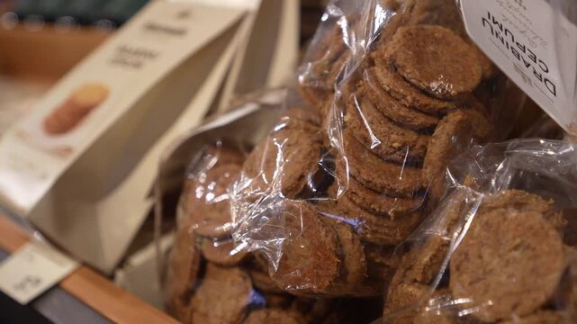 Packaged cookies displayed in a store, showcasing layers of biscuits in transparent wrapping with branding visible on the packaging