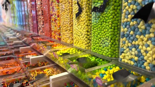Abundant assortment of colorful candies and sweets filling transparent dispensers in a confectionary store, offering a delicious variety of sugary treats for customers to choose from