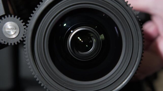 Videographer's hand controls focus of camera lens close-up