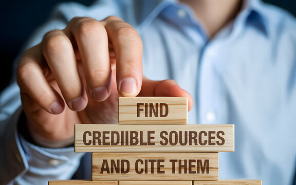 Hand stacking wooden blocks with text "find credible sources and cite them