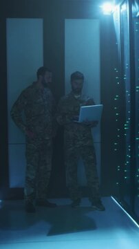 Caucasian military personnel collaborate on network diagnostics and strategy planning in bluelit environment