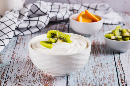 Thick fermented skim milk product with probiotics and kiwi in a bowl on the table