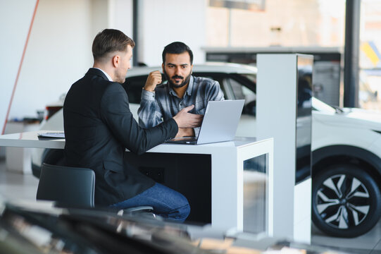 Car salesman discussing financing with customer at dealership