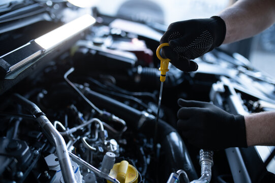 Mechanic checking car engine oil level with dipstick
