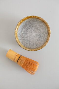 Matcha preparation bowl with a textured gray interior and a bamboo whisk placed beside it on a light surface, ideal for tea ceremonies or culinary use