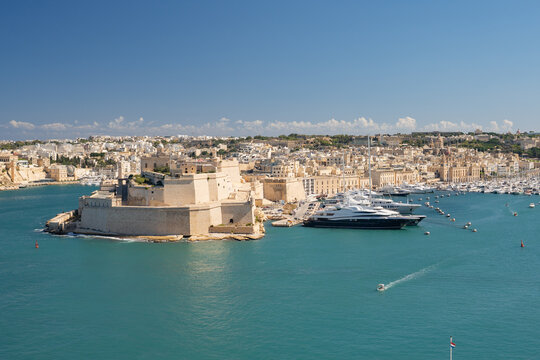 Horizontal panoramic view of Fort St. Angelo and luxury yachts in the Grand Harbour. Historic architecture of Birgu, Malta.