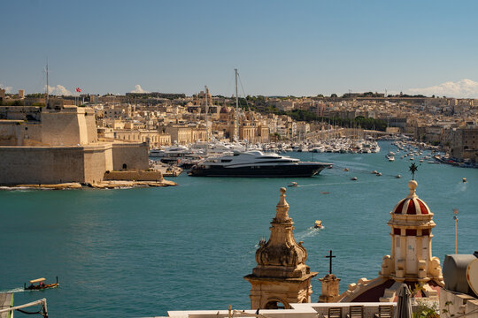 Horizontal panoramic view of the Grand Harbour with luxury yachts and Fort St. Angelo. Historic cityscape of Valletta and Birgu, Malta.