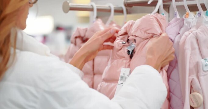 Woman Shopping for Pink Winter Coats in a Mall