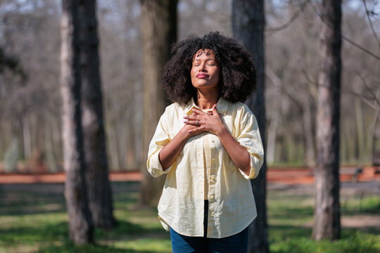 African woman practices breathing in forest during sunny day