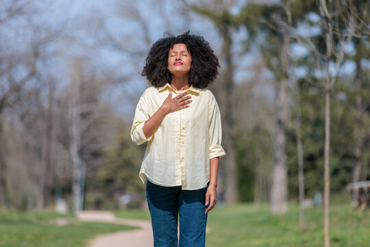 Woman practices grounding pose and breathing in the park during sunny day