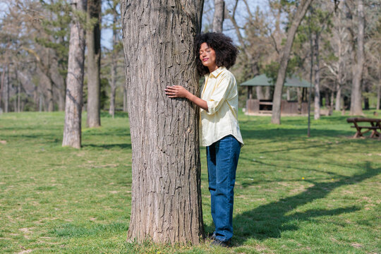 African woman enjoys hugging a tree in the park