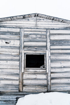 Svalbard, Svalbard and Jan Mayen - 21 June 2025: View of the weathered wooden facade of Kinnvika Station with an open window and snow at the base.