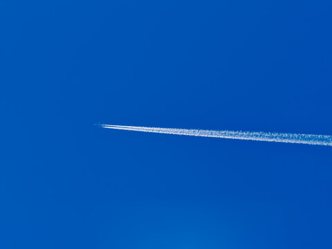 Clear blue sky with airplane's contrail streaking across
