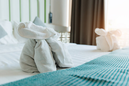 Towel animal elephant on hotel bed with teal runner and soft morning light for hospitality room background and welcome display