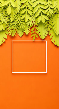Paper leaves, green and crafted, rest above a white square frame on an orange background, representing tropical nature and space for message
