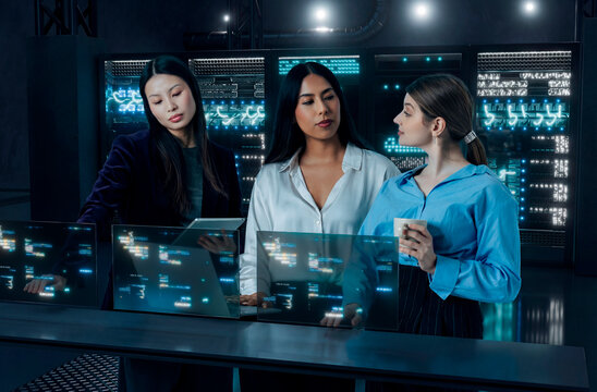 Developer women reviewing code on holographic screens in 3D server room