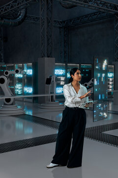 Engineer woman operating robotic systems with holographic interface in 3D facility