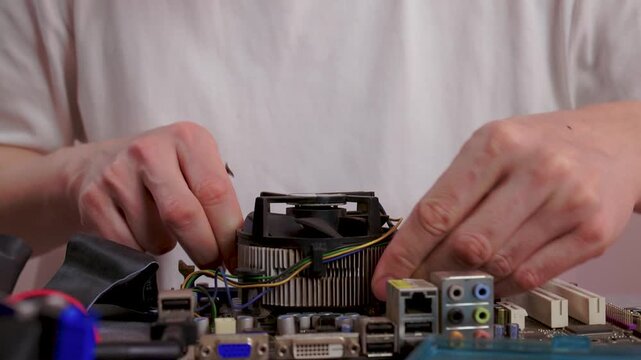 Hobbyist meticulously fixing processor and cooling unit in detailed workspace. Precise hands gently assembling computer parts with focus and care in workshop setting