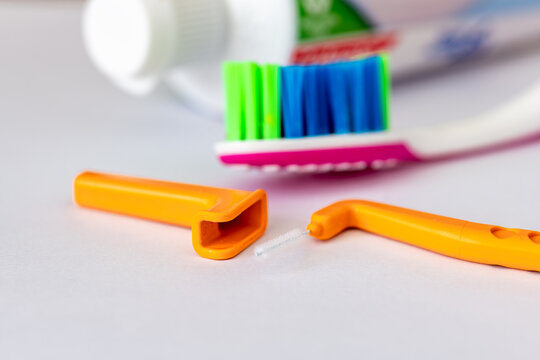 A close up of an angle interdental brush, a tooth brush and tooth paste isolated on white.