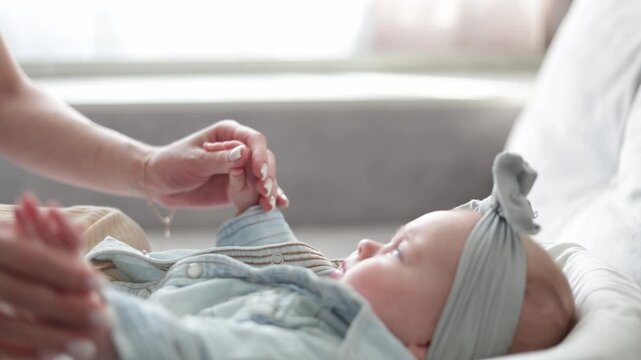 Gentle mother's hands caring for a newborn baby in a cozy bassinet