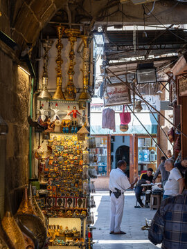 Cairo, Egypt - 20 April 2026: View of the historic Khan el-Khalili bazaar with shops selling traditional hookahs and souvenirs along a narrow alleyway filled with people.
