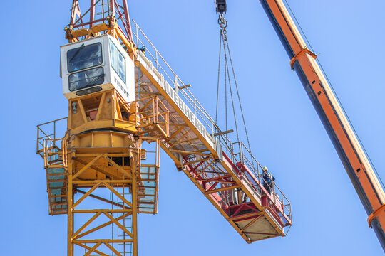  Poznan, Polska - April 23, 2026: Liebherr crane with a long arm hoisting a load against a bright blue sky