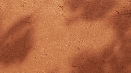 Fototapeta premium Rich warm terracotta clay wall texture with natural shadow gradients. Earthy red-brown surface background for boho, wellness, pottery, and summer brand campaigns 2026.