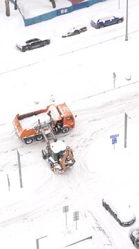 Snow removal operation on urban street with machinery clearing snow and slush from roads and parking areas, highlighting winter city maintenance and icy road conditions
