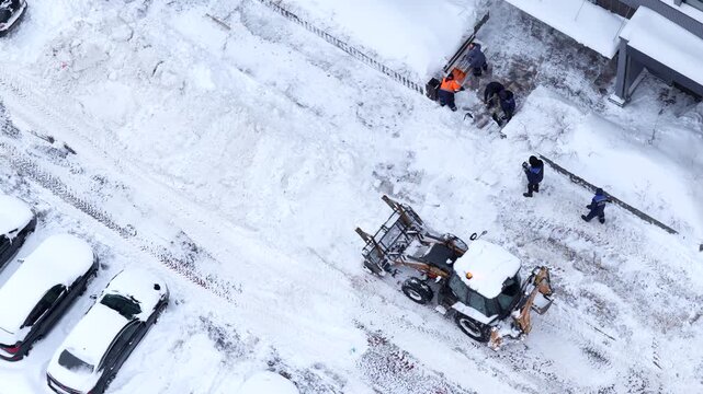 Snow removal operation in urban parking area with machinery clearing slush and snow, highlighting winter city maintenance and urban infrastructure