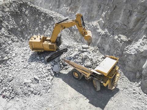 Santa Lucia de Gordon, Spain: View of a large yellow excavator parked in a quarry under a clear blue sky.