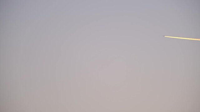 High Altitude Aircraft Leaving Vapor Trail in Sky. Airplane Crossing Blue Sky with Long White Trail. Jet Stream Trail Behind Airplane in Clear Sky. Minimal Sky Scene Plane and Contrail Motion. 