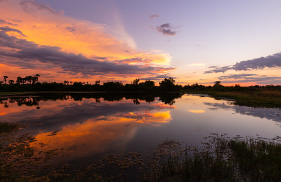 Beautiful sunset over calm lake with dramatic orange sky and water reflection for natural landscape and travel background design