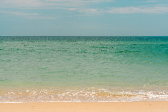 Gentle waves rolling onto sandy beach under clear sky
Caption: