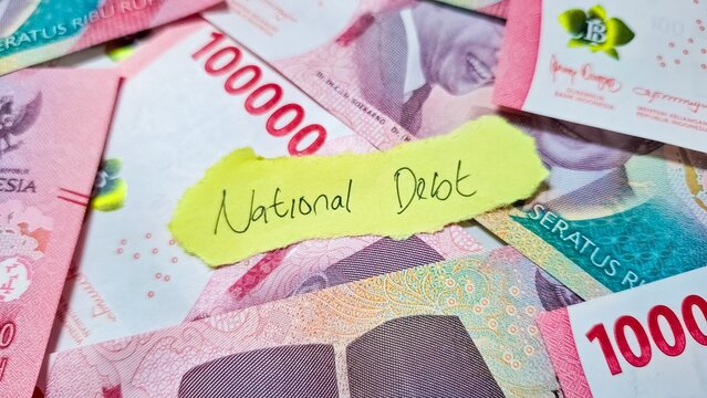 Indonesian rupiah banknotes with a National Debt note, symbolizing economic burden.