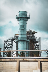 Obraz premium Industrial power plant with tall smokestack against a cloudy sky
