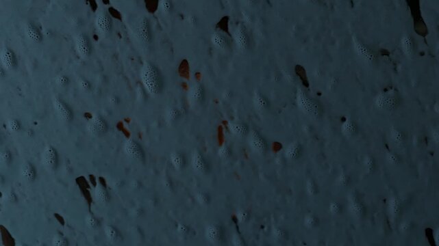 Close-up view of textured surface with bubbles and irregular patterns transitioning from light to dark shades, showcasing the gradual change in appearance and color depth