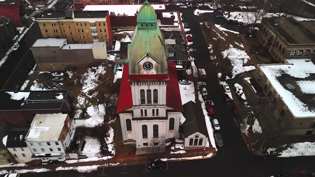Aerial descent toward clock tower facade above snowy downtown streets