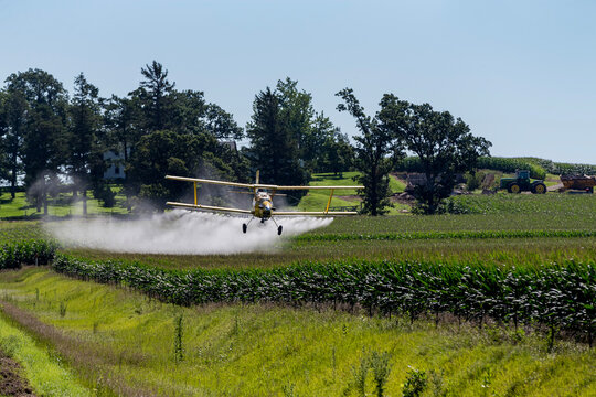 Yellow Crop Duster Sprays Fields Beneath Clear Sky