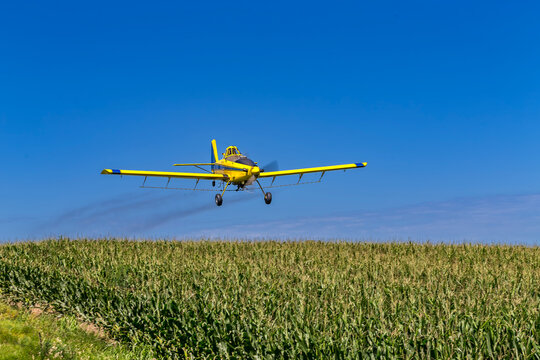 Yellow Crop Duster Sprays Fields Beneath Clear Sky