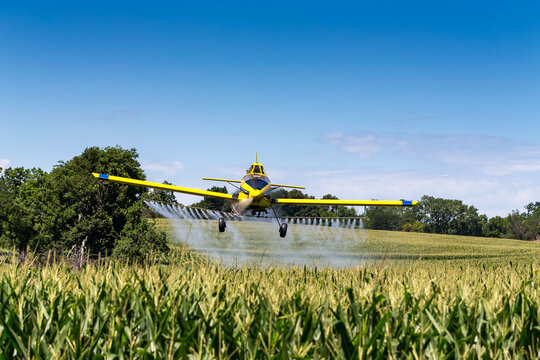 Yellow Crop Duster Sprays Fields Beneath Clear Sky