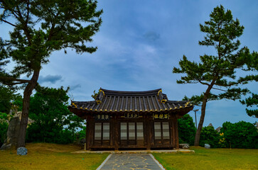 Obraz premium Traditional Korean pavilion surrounded by greenery under cloudy sky. Cultural heritage and architecture concept.