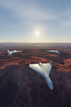 Unmanned Stealth Drones Flying in Formation Over Desert Canyon at Sunrise 3D Rendering
