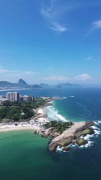 Arpoador Beach and Arpoador Rock with Copacabana in the background and the city of Rio de Janeiro on a sunny day with clear waters