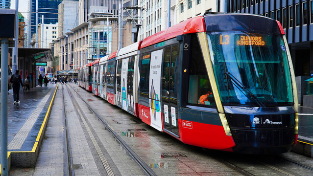 Light train in Sydney,  Most modern public transport which replaced tram in Australia.Light rail vehicle travels along the tracks in a busy city area during the daytime with many people nearby