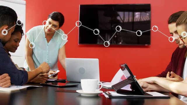 Five-member team planning, lead leaning, pointing phone, graph animating on red wall, updating data