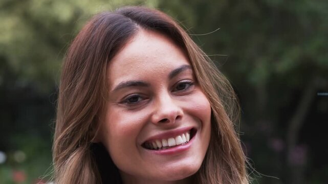 Woman in park glancing upward and smiling, initiating HUD rings pulsing across face, showing AR