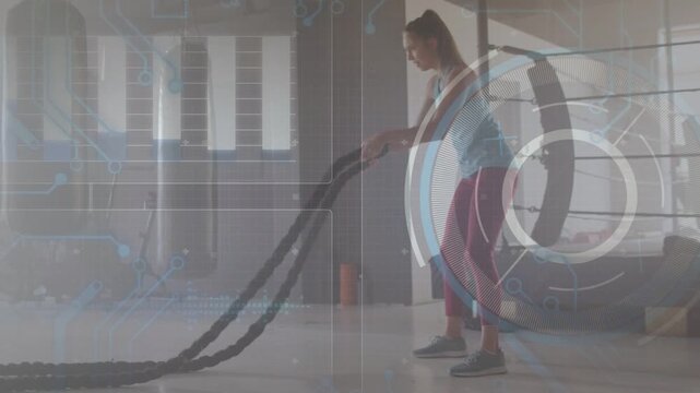 Female trainee gripping ropes, generating waves in gym while HUD showing metrics, building power