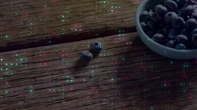 Blueberry bowl static two berries with specks appearing drifting across wood table making glow
